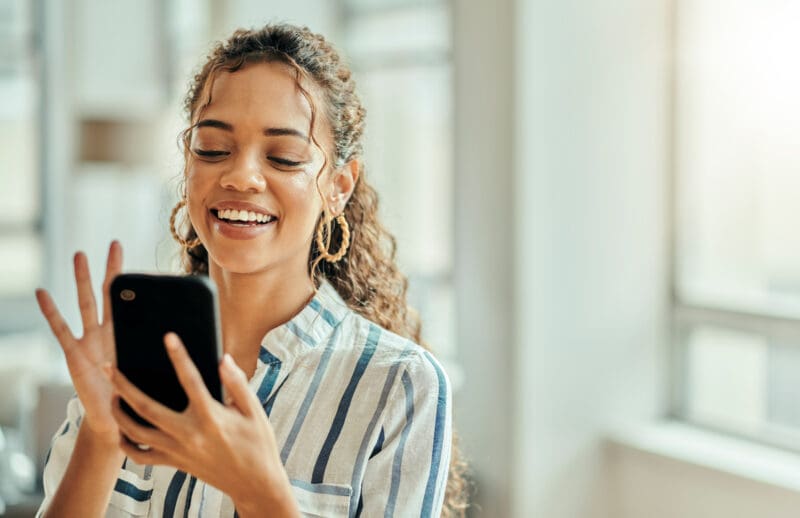 Smiling woman looking at her smartphone in a bright indoor setting
